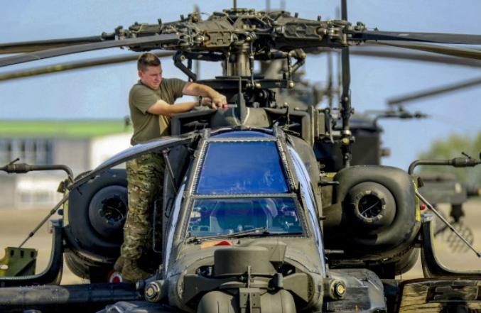 A U.S. Soldier conducts routine maintenance on a AH-64 Apache helicopter 